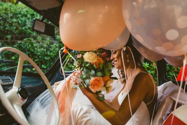 La sposa a bordo di una Fiat 500 con il bouquet e palloncini nel matrimonio Villa Bossi Varese.