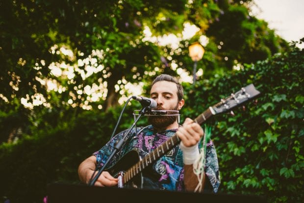 Un musicista suona chitarra e armonica durante l’aperitivo a Villa Bossi.