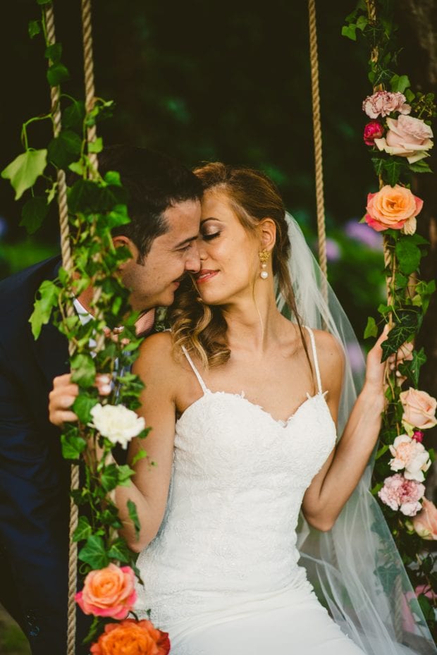 Gli sposi si scambiano un bacio romantico mentre la sposa è su un’altalena a Villa Bossi.