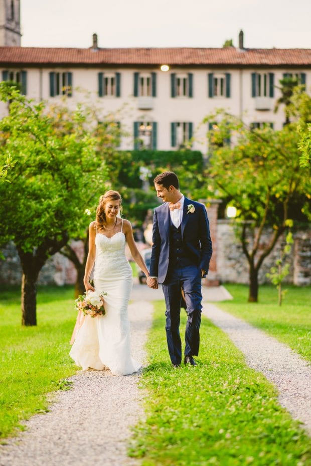 Gli sposi camminano mano nella mano nei prati intorno a Villa Bossi durante il matrimonio.