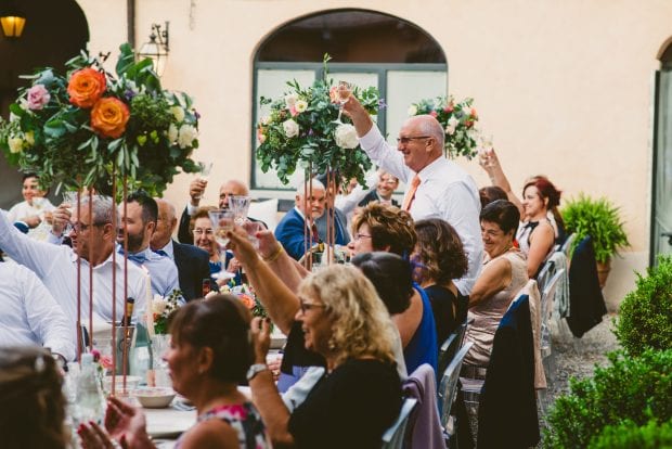 Gli invitati alzano i calici per un brindisi di augurio agli sposi nel cortile di Villa Bossi.