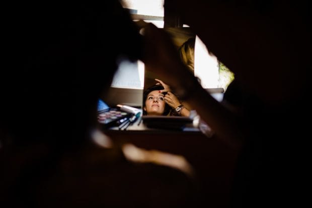 Riflesso della sposa nello specchio mentre si trucca nel suo giorno speciale a Villa Bossi.