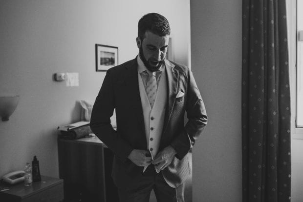 Lo sposo indossa la giacca con eleganza durante la preparazione a Villa Bossi.