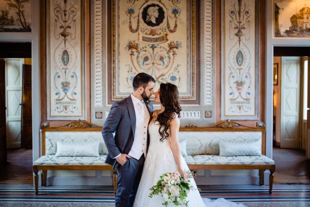 Gli sposi si guardano con amore nella sala affrescata di Villa Bossi, immersi in un’atmosfera storica e romantica.