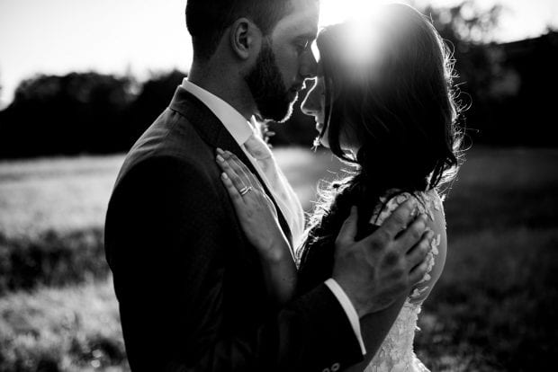 Gli sposi fronte a fronte con la luce del tramonto, in un ritratto in bianco e nero emozionante e intenso.