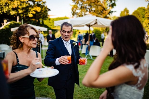 Il padre dello sposo con due spritz in mano durante il ricevimento a Villa Bossi.