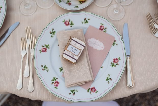 Menù personalizzato posato accanto a un piatto elegantemente apparecchiato a Villa Bossi.