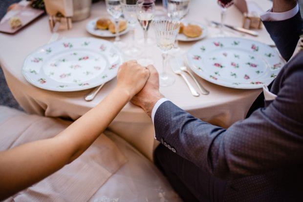 Gli sposi si tengono per mano mentre ascoltano l’esibizione del tenore a Villa Bossi.
