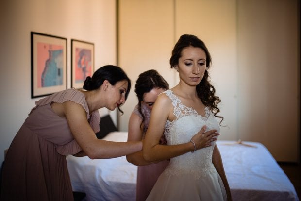 La sposa indossa il suo abito aiutata dalle damigelle