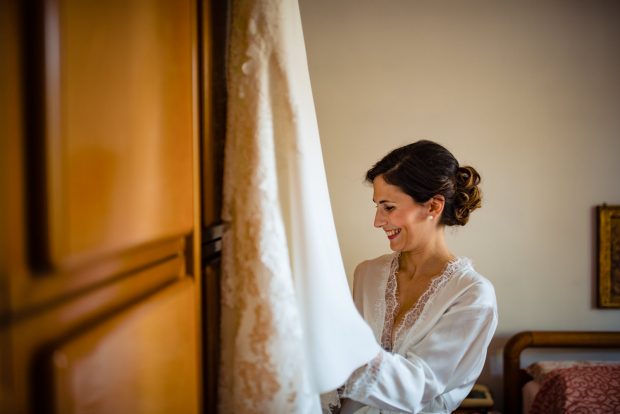 La sposa osserva emozionata il suo abito da sposa prima di indossarlo nel giorno del matrimonio a Tenuta Serradesca.