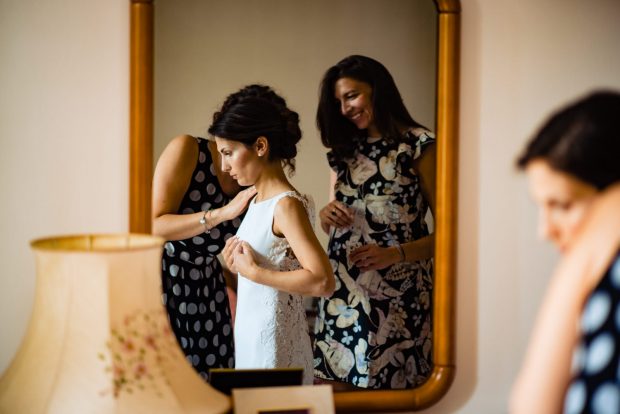 La sposa indossa il suo abito, il suo riflesso nello specchio cattura tutta l’emozione del momento.