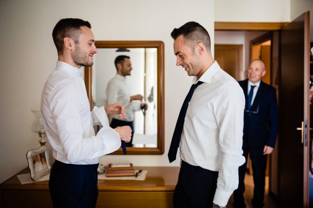 Lo sposo e suo fratello condividono un momento di complicità e risate durante i preparativi del matrimonio a Tenuta Serradesca.