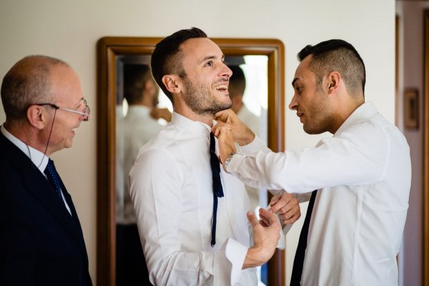 Il fratello dello sposo sistema con cura il nodo del papillon in un gesto simbolico di affetto prima della cerimonia.