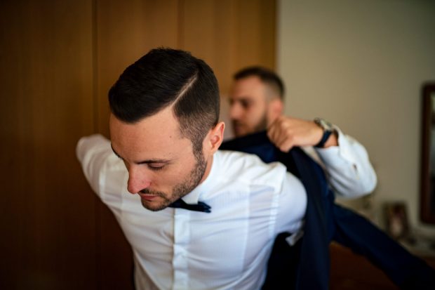 Lo sposo si prepara con eleganza, indossando il panciotto per completare il suo look raffinato.