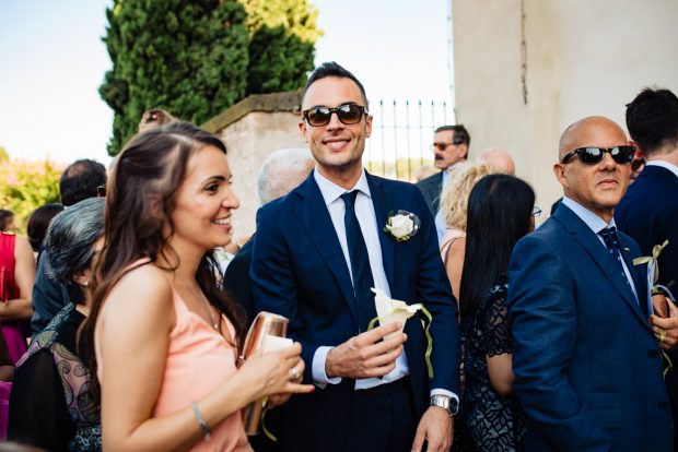 Gli invitati sorridono con il riso tra le mani, pronti a celebrare gli sposi fuori dalla chiesa.