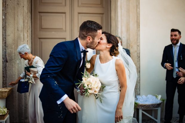 Gli sposi si scambiano un bacio romantico tra i chicchi di riso ancora nell’aria.