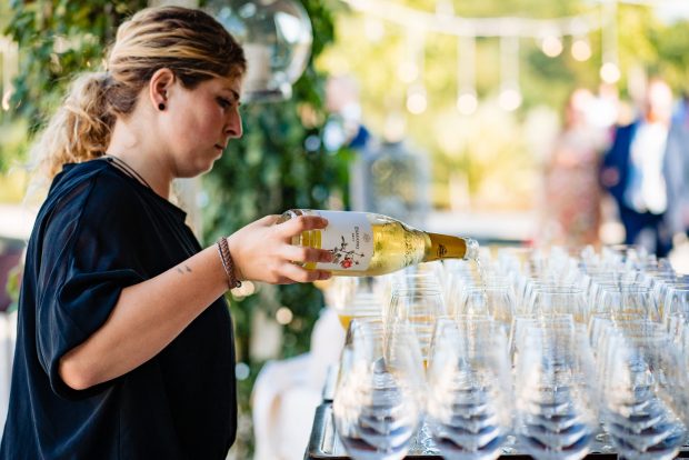 Un cameriere versa Franciacorta in calici eleganti, brindisi di classe per un matrimonio esclusivo.