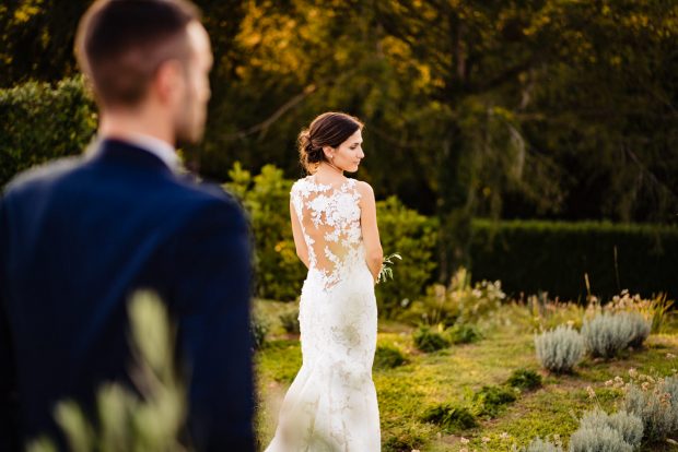 Dettaglio raffinato dell’abito da sposa visto da dietro, con giochi di luce che esaltano il design elegante.