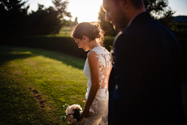La sposa cammina dolcemente al tramonto nei giardini di Tenuta Serradesca, avvolta in una luce dorata.