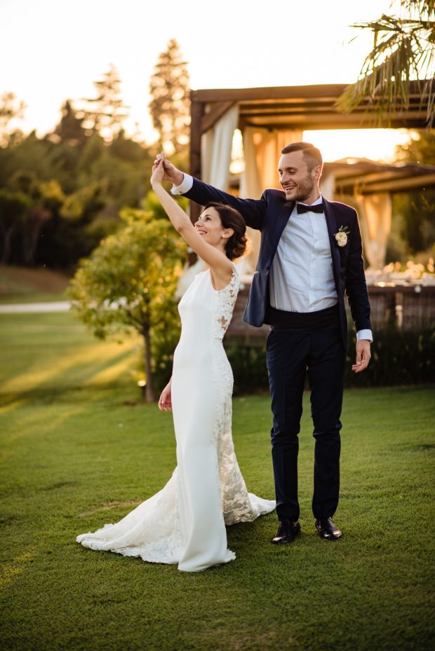 Gli sposi si lasciano andare a un ballo romantico nel prato al tramonto, immersi nella loro felicità.