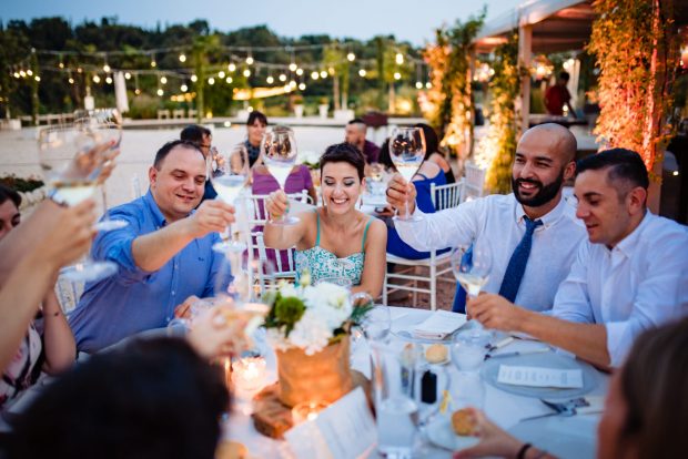 Gli amici degli sposi brindano a tavola, condividendo un momento di festa e allegria.