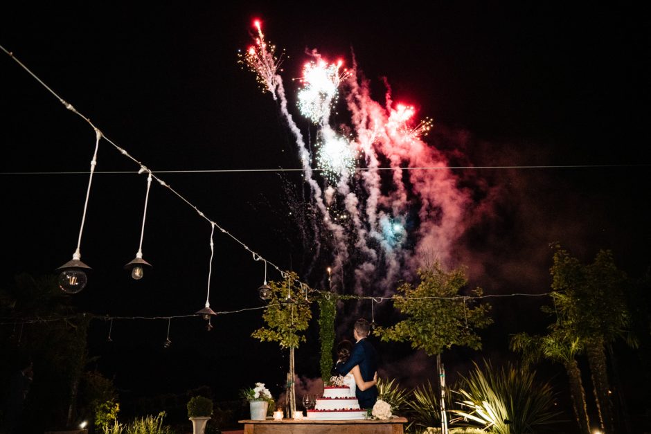 Gli sposi tagliano la torta sotto uno spettacolo di fuochi d’artificio, un momento spettacolare e indimenticabile.