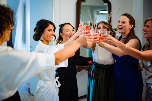 Un brindisi di gioia tra la sposa e le sue amiche prima di indossare l’abito da sposa.