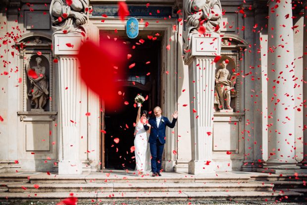 Gli sposi escono dalla chiesa accolti da una pioggia di riso e petali rossi.