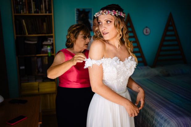 Madre della sposa che allaccia con dolcezza il vestito nuziale, un momento emozionante del matrimonio a Villa Calchi.