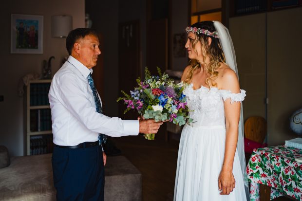 Il padre della sposa le porge il bouquet con emozione prima della cerimonia a Villa Calchi.