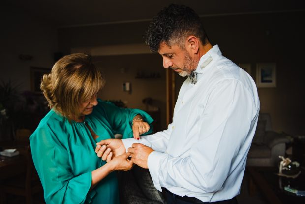 La mamma dello sposo allaccia con cura i gemelli, un momento di dolcezza catturato dal fotografo matrimonio Varese Villa Calchi.