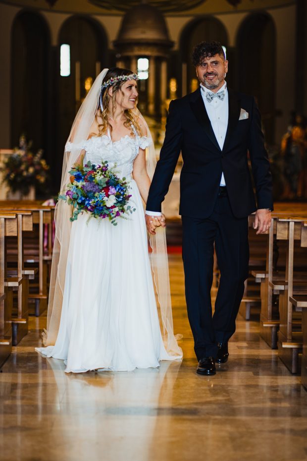 Gli sposi escono mano nella mano dalla chiesa dopo la cerimonia, catturati dal fotografo matrimonio Varese Villa Calchi.