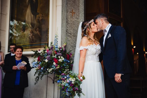 Gli sposi si baciano emozionati dopo il lancio del riso, un’immagine romantica del matrimonio a Villa Calchi. Fotografo matrimonio Varese Villa Calchi.