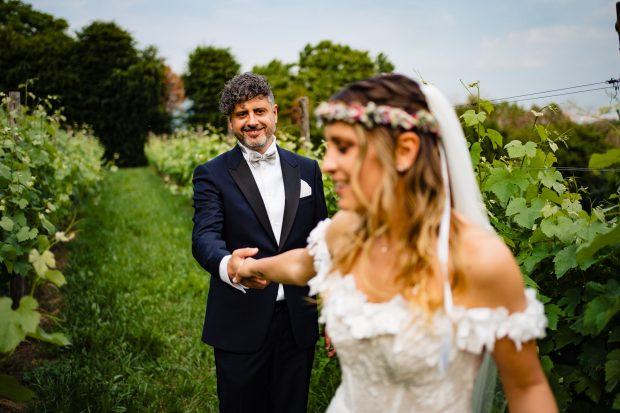 La sposa prende per mano lo sposo e lo guida tra i vigneti di Villa Calchi, un momento di sintonia perfetto. Fotografo matrimonio Varese Villa Calchi.