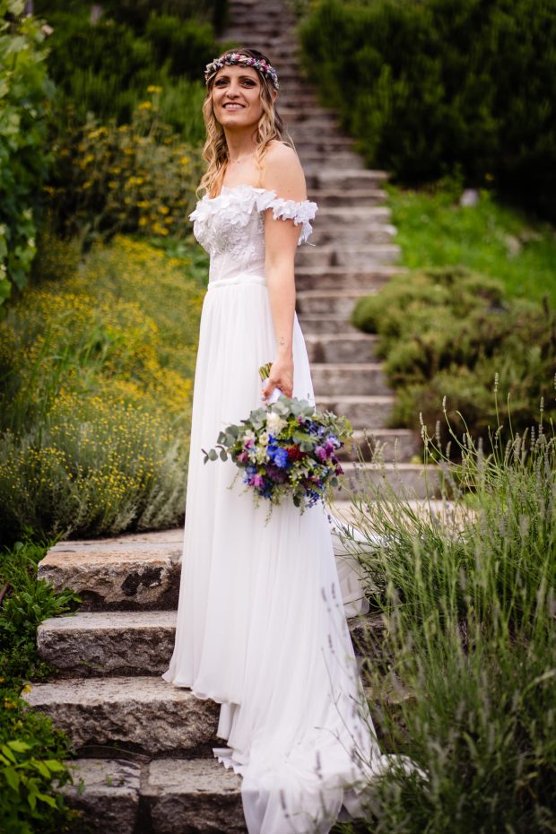 La sposa posa con eleganza su una scala decorata con lavanda, un ritratto raffinato del matrimonio a Villa Calchi. Fotografo matrimonio Varese Villa Calchi.