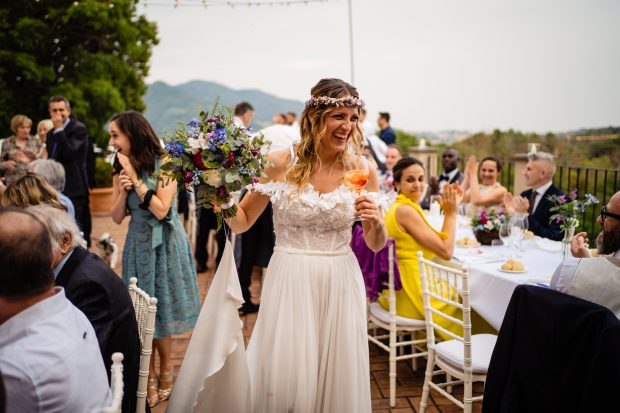 La sposa cammina tra i tavoli ridendo, circondata dagli invitati felici al matrimonio a Villa Calchi. Fotografo matrimonio Varese Villa Calchi.