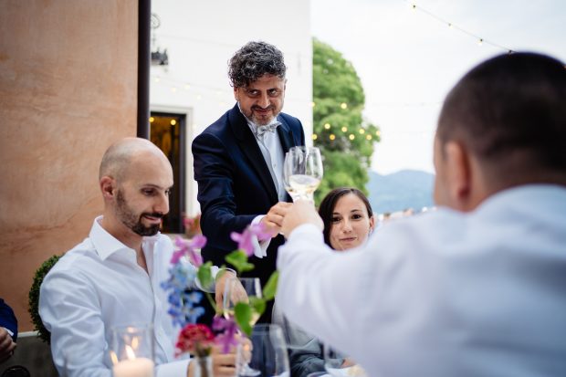 Lo sposo brinda con gli amici durante il ricevimento a Villa Calchi, un momento di festa e complicità. Fotografo matrimonio Varese Villa Calchi.