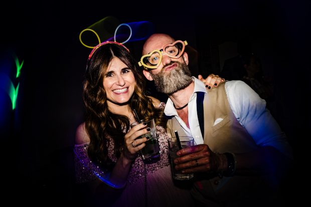 Gli amici degli sposi ballano con occhiali finti e sorrisi contagiosi sulla pista da ballo a Villa Calchi. Fotografo matrimonio Varese Villa Calchi.