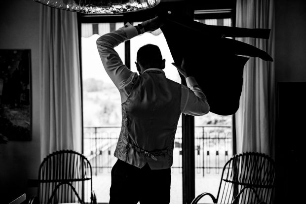 Lo sposo indossa la giacca con stile prima del matrimonio a Villa Antona Traversi.