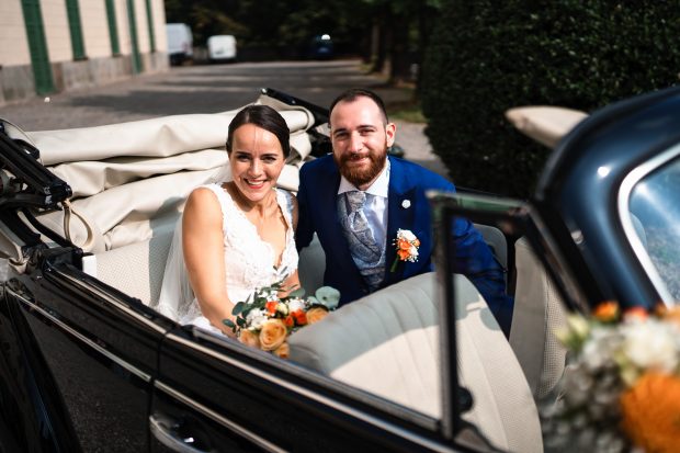 Gli sposi sorridono mentre posano sull’auto del matrimonio a Villa Antona Traversi.
