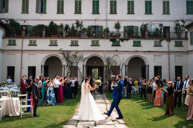Gli sposi arrivano all’aperitivo accolti dagli invitati a Villa Antona Traversi. Lo sposo si lascia andare ed esulta