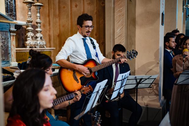 Un momento musicale durante la cerimonia, con musicisti che suonano dal vivo. Fotografia scattata da Paolo Lamperti Fotografo Matrimonio Varese al Castello di Tabiano.