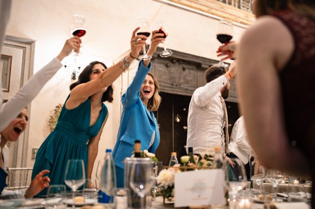 Gli amici brindano sorridenti durante il ricevimento serale del matrimonio di Marika e David