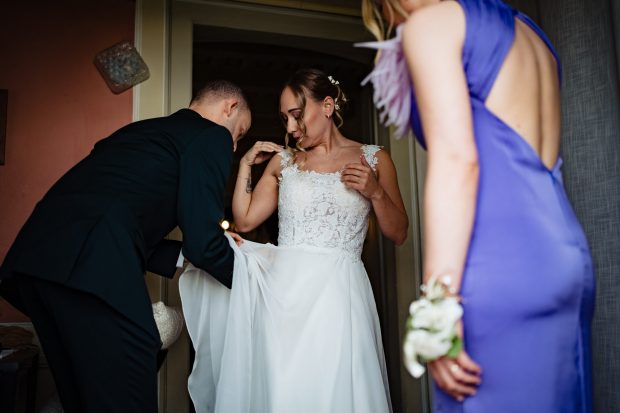 Patrizia che indossa il suo abito da sposa con l'aiuto delle amiche. Scatto realizzata da Paolo Lamperti Photographer Fotografo matrimonio Varese e Tenuta Frizzoni.