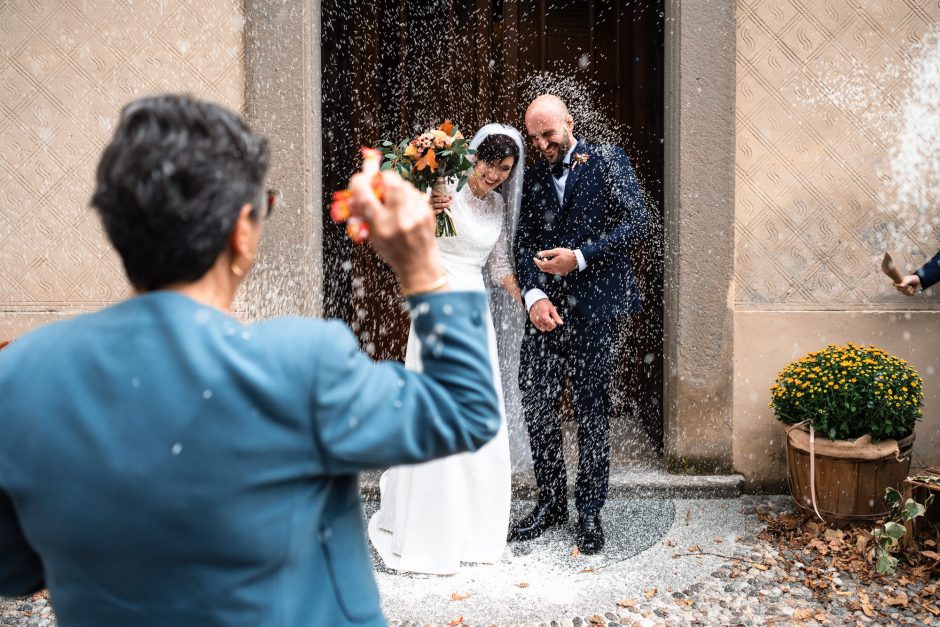 Stefania e Alessandro escono dalla chiesa, circondati da amici e familiari che festeggiano il loro matrimonio con sorrisi e applausi.