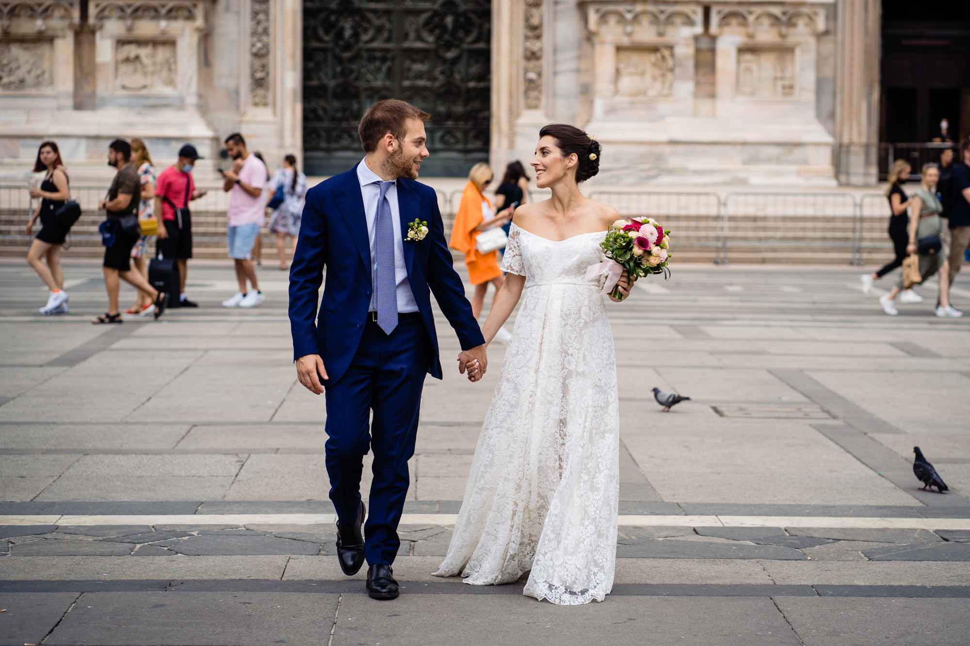 Gli sposi camminano mano nella mano in Piazza Duomo Milano dopo il Matrimonio Chiostri San Barnaba.