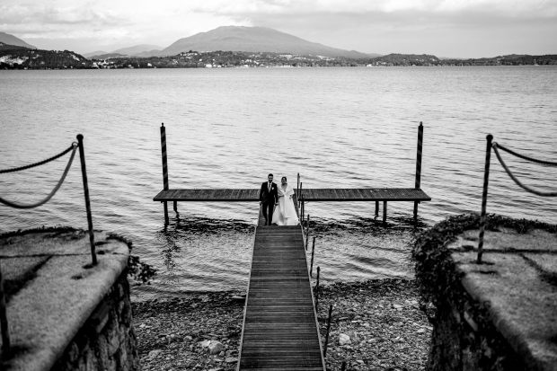 Vista panoramica in bianco e nero degli sposi che rientrano dal pontile, fotografo matrimonio Varese Villa Claudia