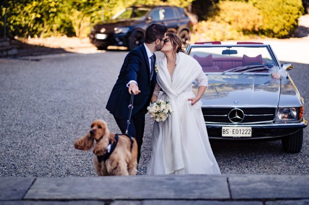 Gli sposi si baciano con il cane al guinzaglio, fotografo matrimonio Varese Villa Claudia