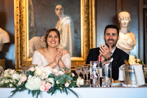 Gli sposi sorridono seduti a tavola a Villa Claudia, fotografo matrimonio Varese Villa Claudia