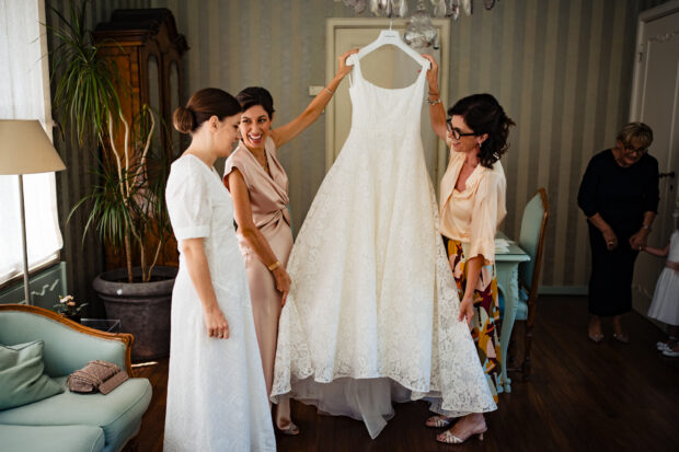 Le amiche della sposa sollevano l’abito prima del matrimonio a Villa Gaia Gandini.